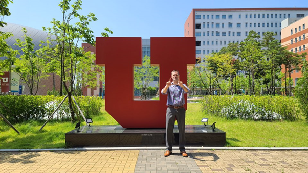 Dr. Greg Hill throws up his U in front of Block U outside of The UAC Building on Incheon Global Campus. (Photo Courtesy of @tuyu_uac on Instagram)