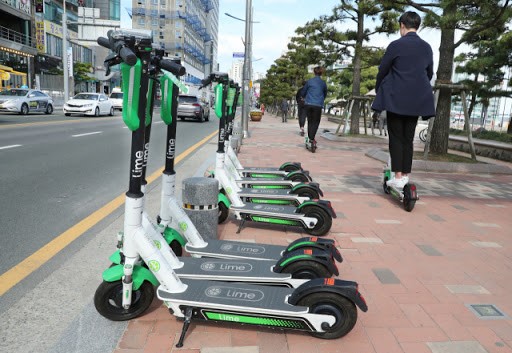 Users pass by a shared company's electric kickboard parked on the beach of Gwangalli Beach in Suyeong-gu, Busan (Credit: Google Image)